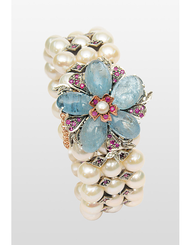 A pearl bracelet with aquamarine and ruby clasp