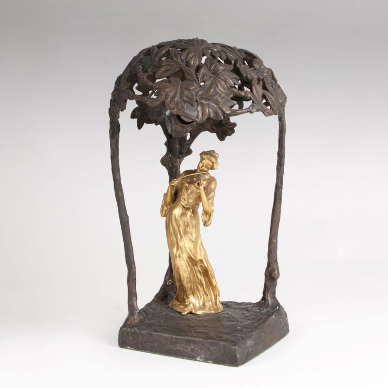 An Art Nouveau table lamp with a female violinist