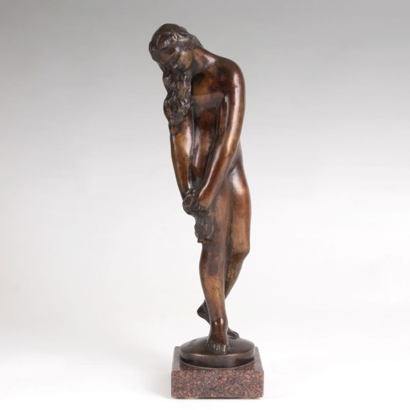 A bronze figure of a female nude holding a cloth