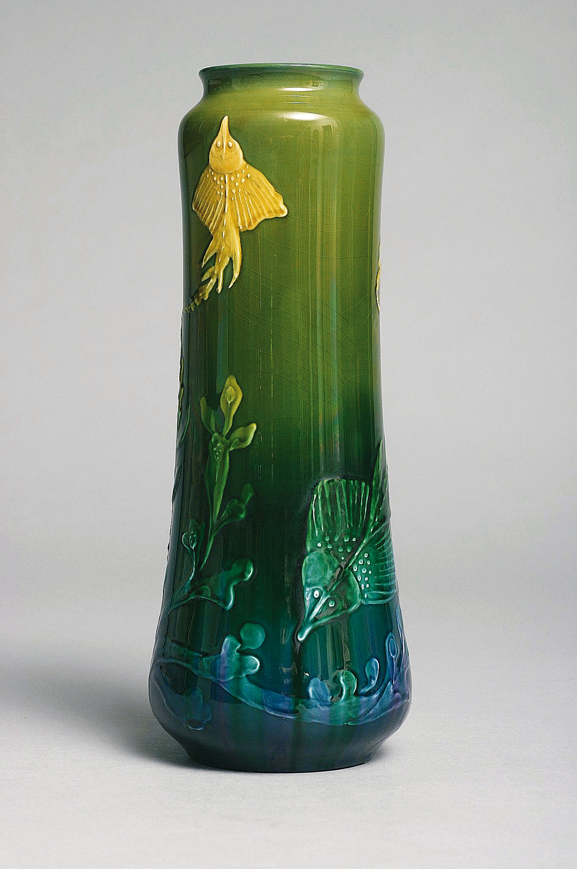 An art-nouveau vase decorated with ray fish within underwater landscape