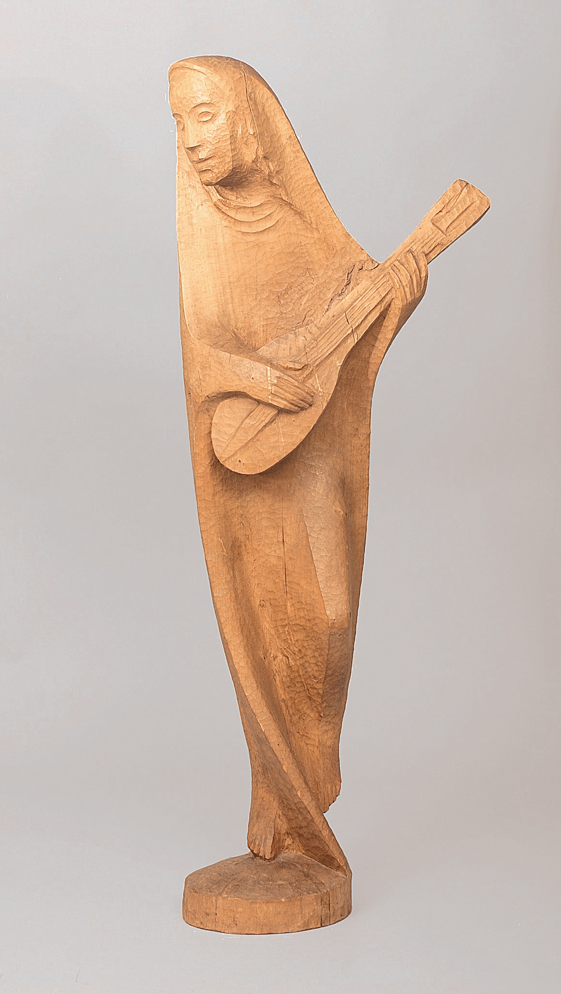 A wooden sculpture of a woman playing the mandolin