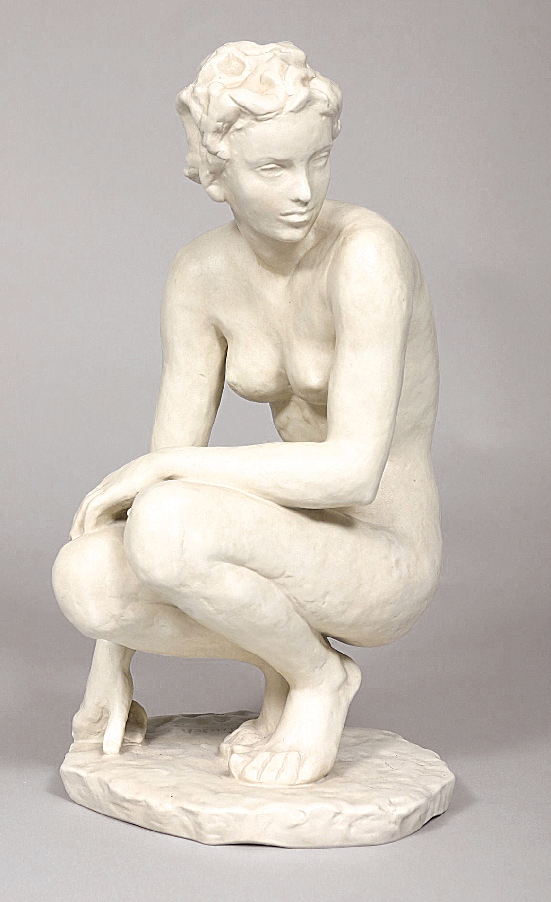 A figure of a crouching nude in biscuit porcelain