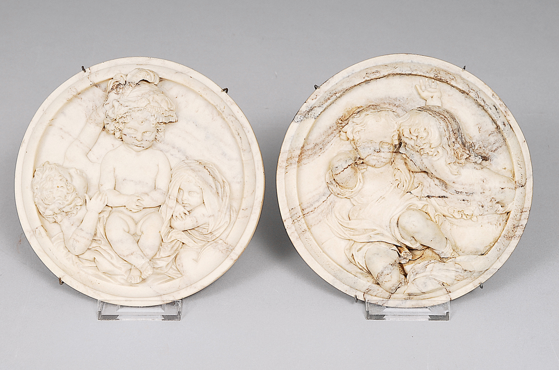 A pair of rare marble tondi wuth playing putti