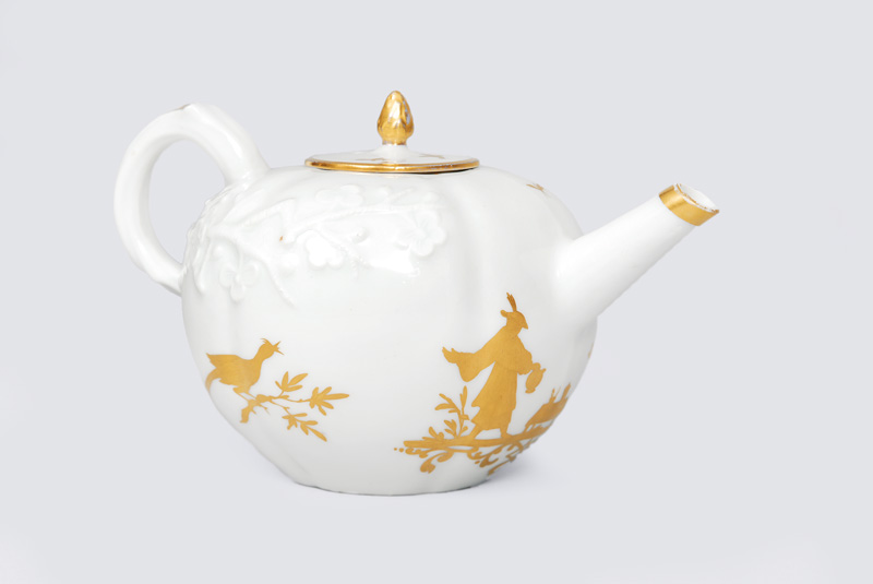 A small teapot with gold Chinoiserie and leaf relief