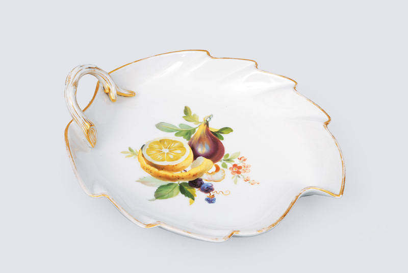 A leaf-shaped bowl with fruit painting and gilded rim