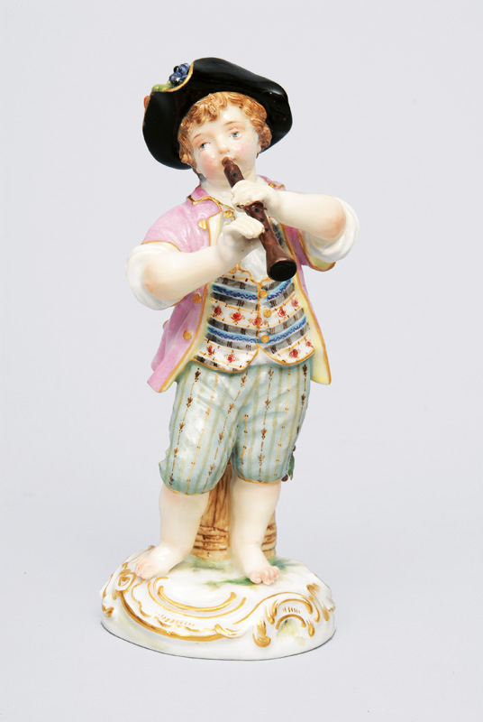 A figurine "Gardener"s child playing the flute"
