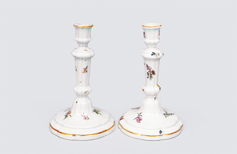 A pair of candlesticks witg flowers and basket relief