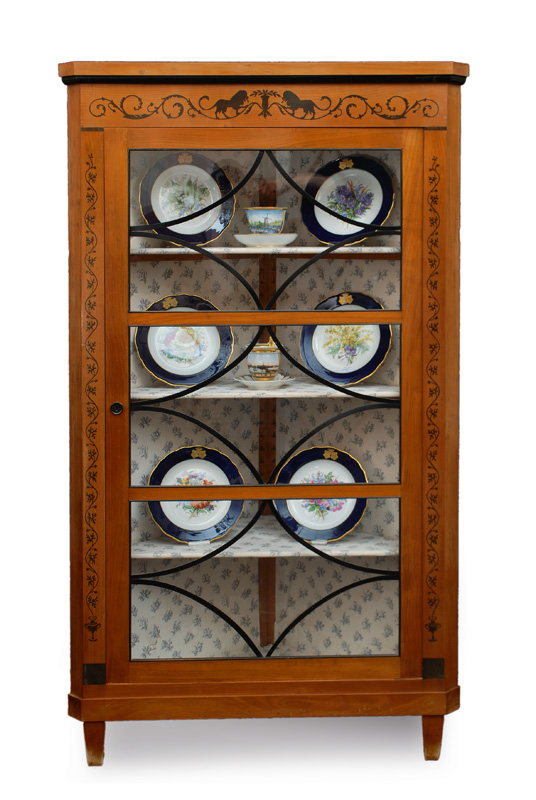 A corner glass cabinet with black stain friezes