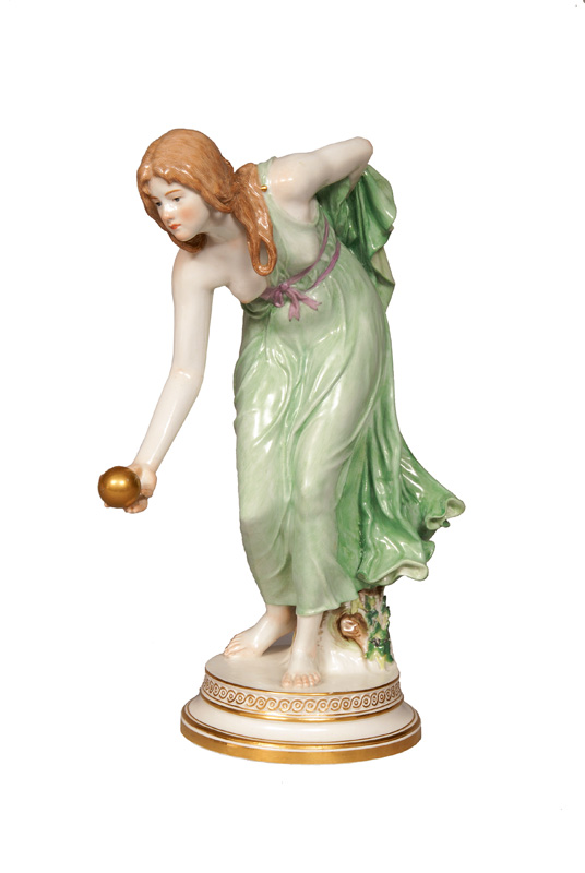 An Art Nouveau figurine of a woman playing ball