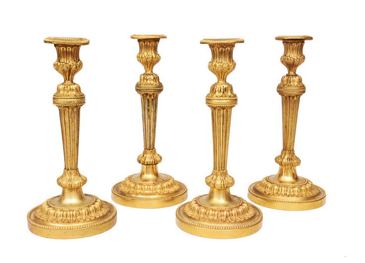 A rare set of four firegilded Empire candleholders