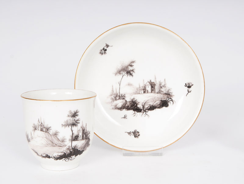A cup and saucer with grisaille landscape