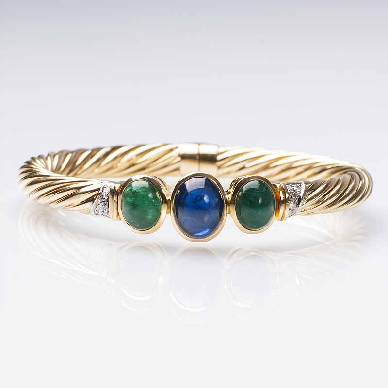 A golden bangle bracelet with sapphires and emeralds
