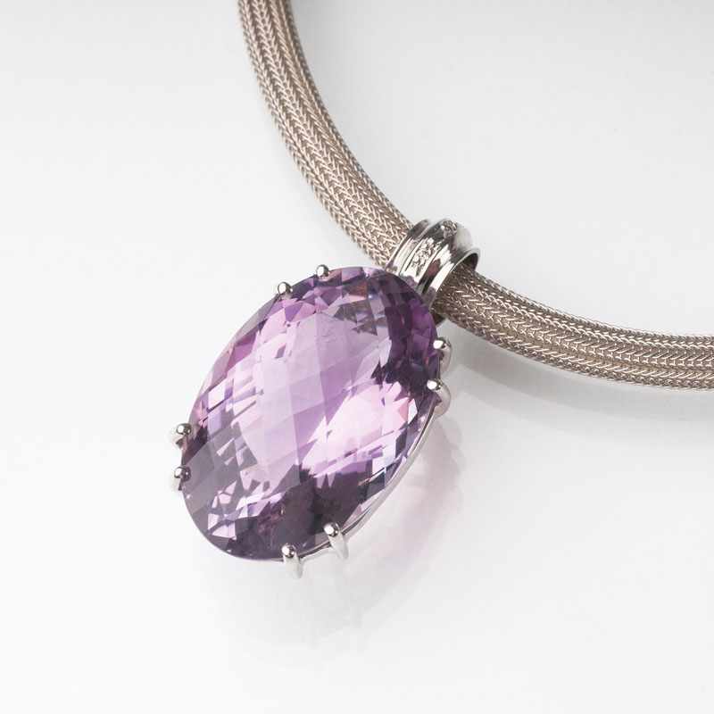 A golden necklace with large amethyst pendant