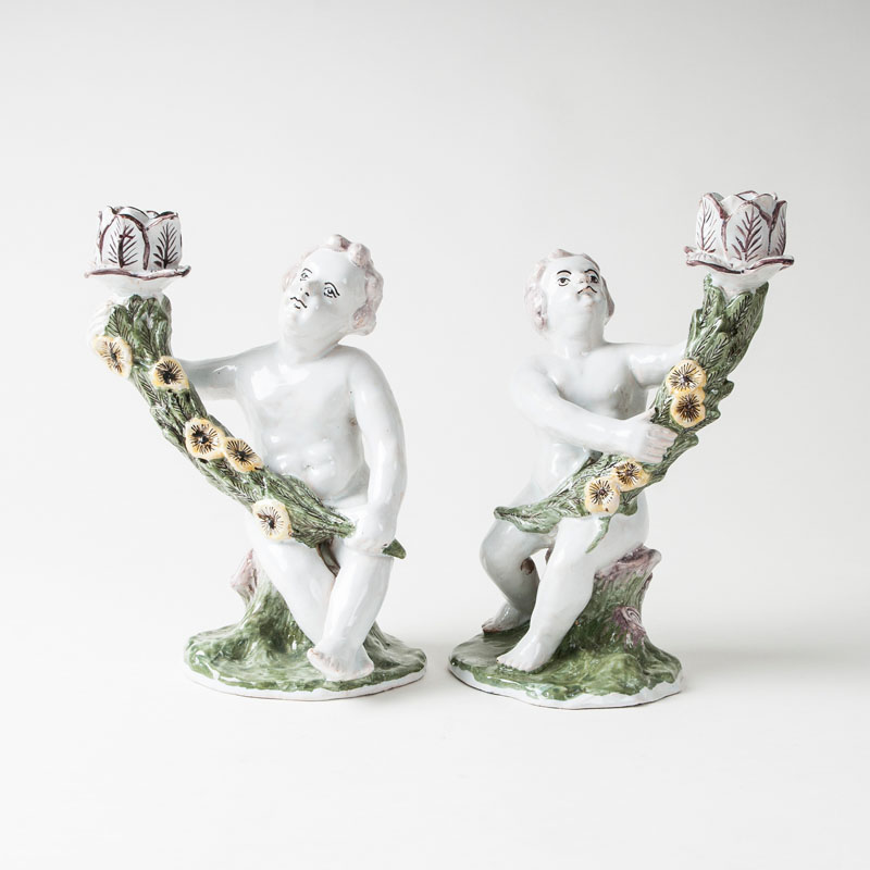 A pair of faience candlesticks with putti