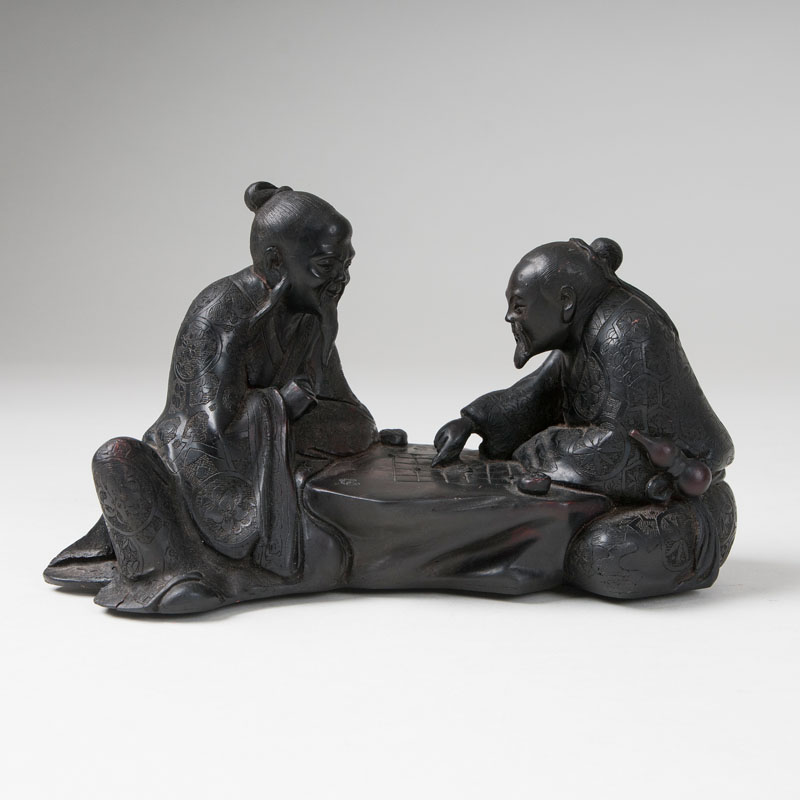 A wood sculpture 'Two men playing a board game'
