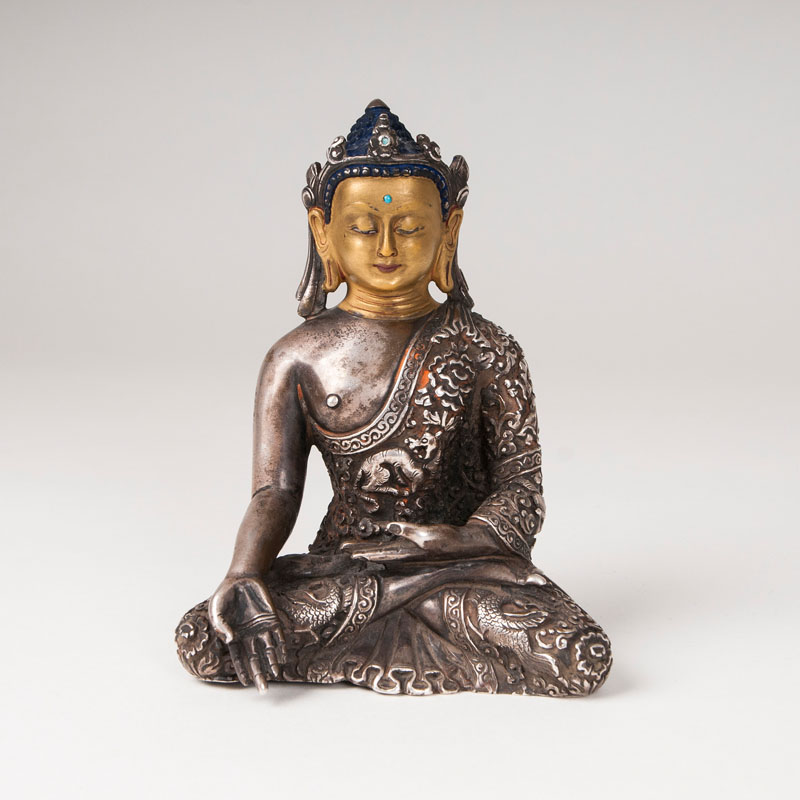 A silver sculpture of a buddha