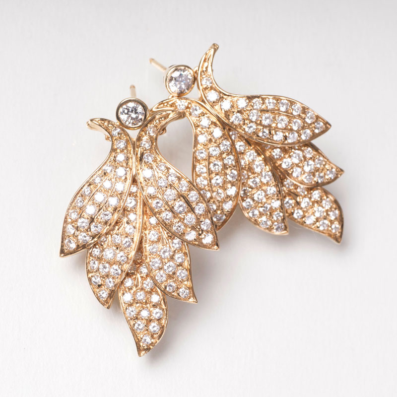 A pair of leaf shaped gold earrings with diamonds
