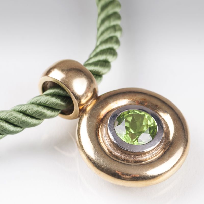 A golden pendant with peridot and two cord necklaces