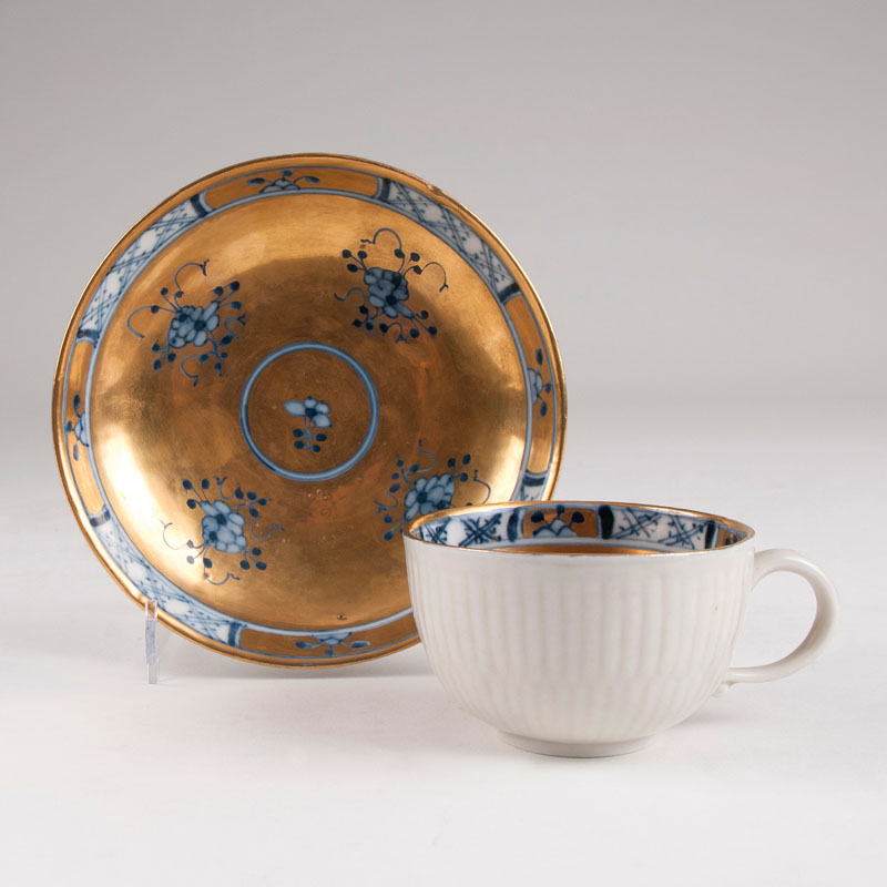 A cup with blue strawflowers and gold ground