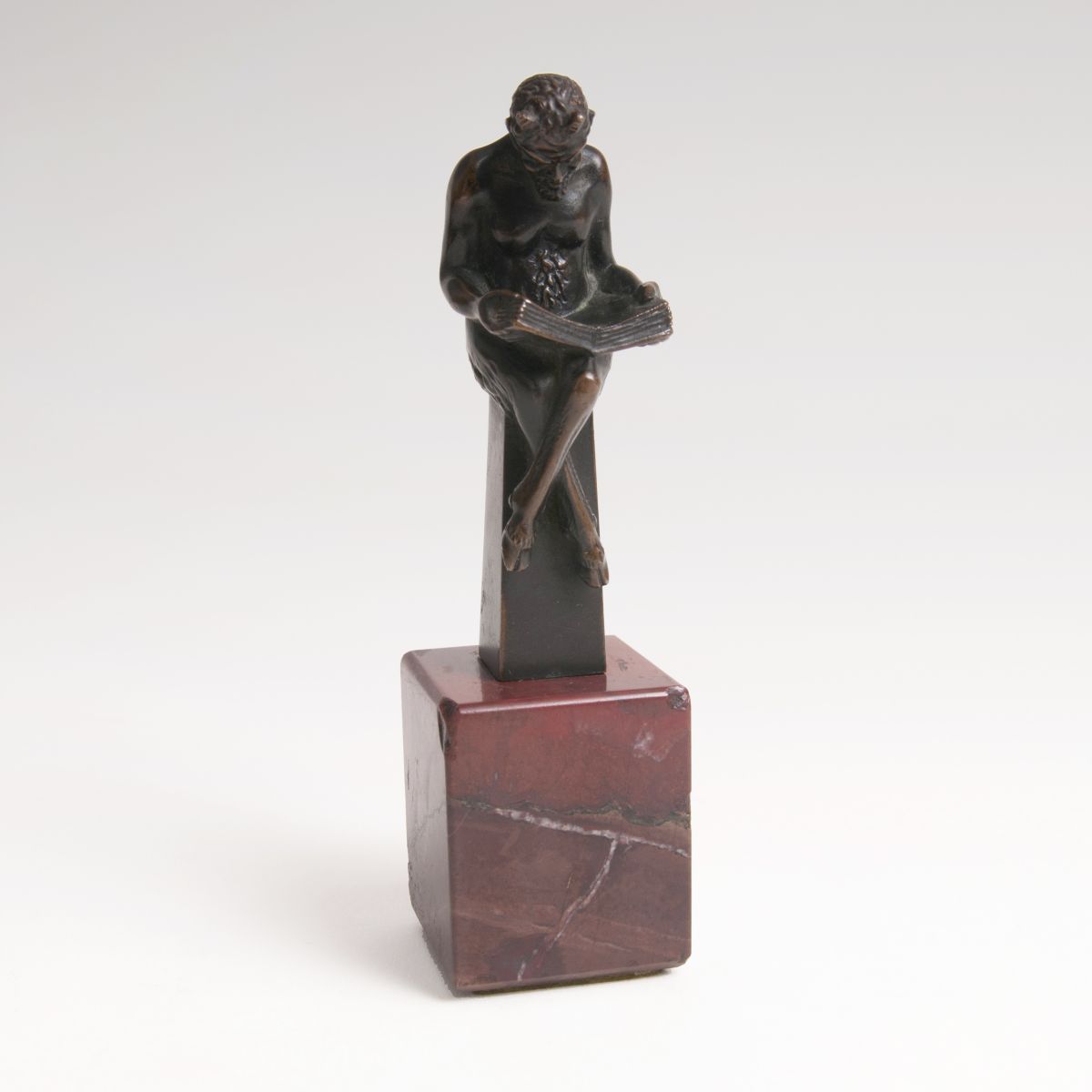 A small bronze 'Reading faun'