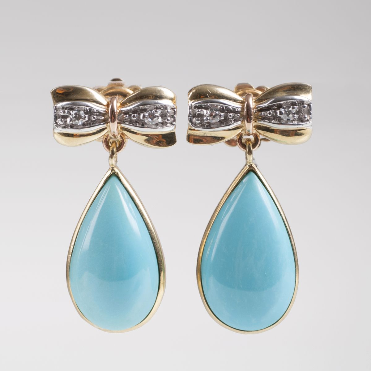A pair of earrings with turquoise and ribbon decor