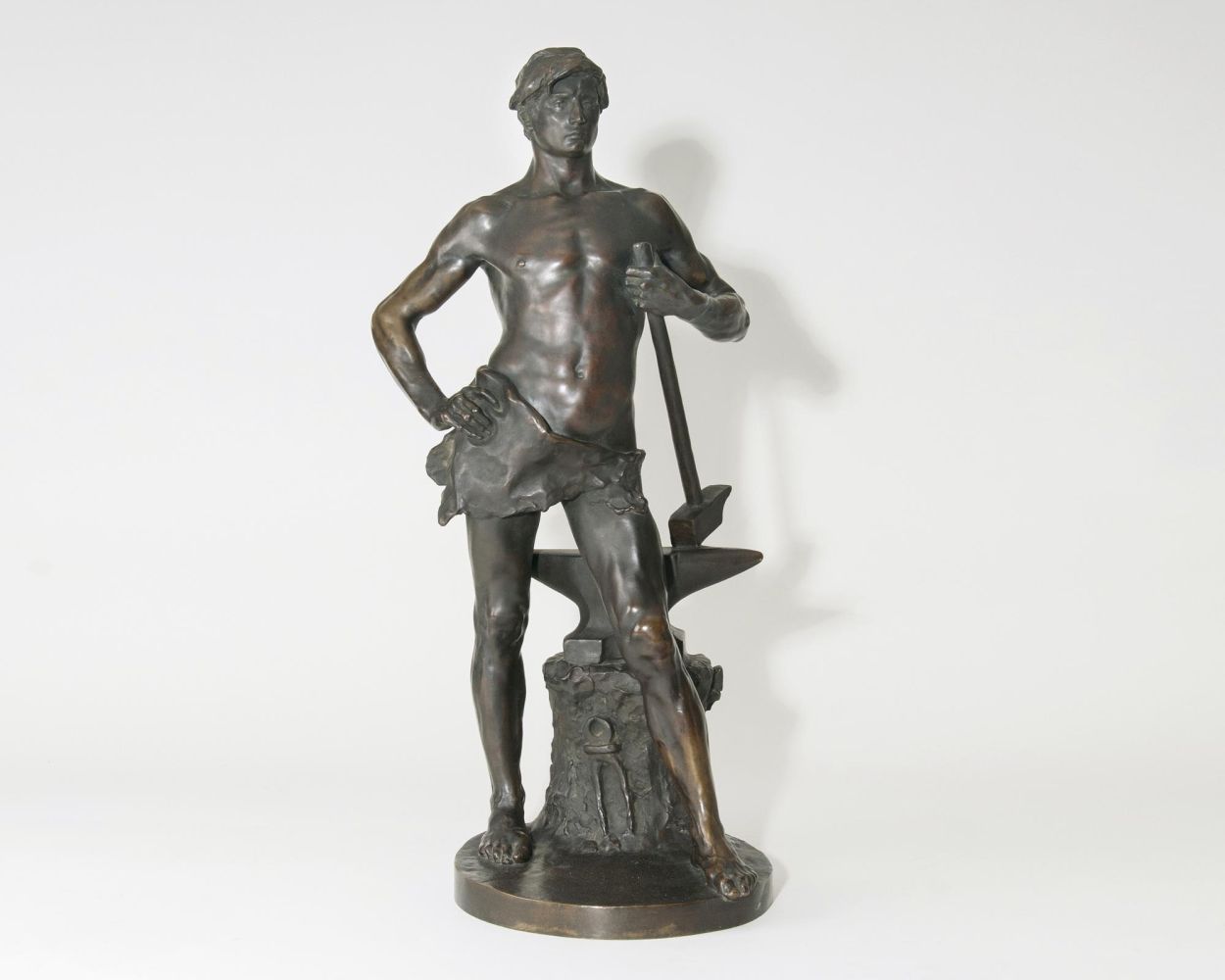 A Large Figure  'Blacksmith standing beside a tree trunk with an anvil, holding a mallet'