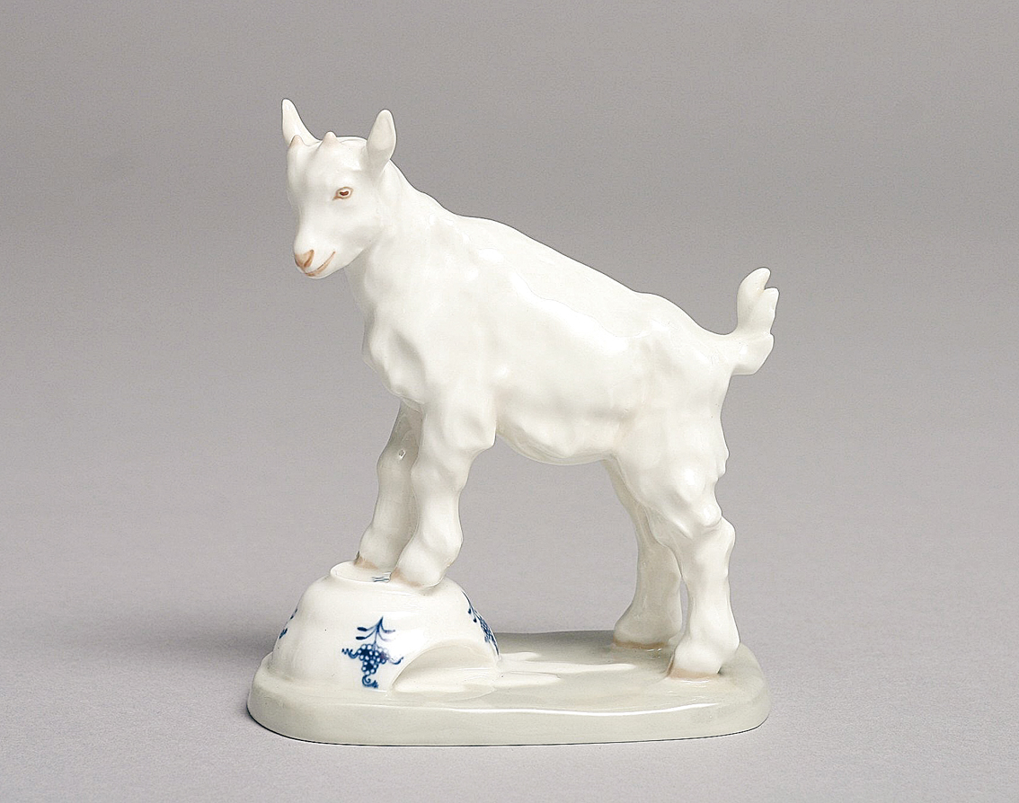 An animal figure 'goat on turned over milk bowl'