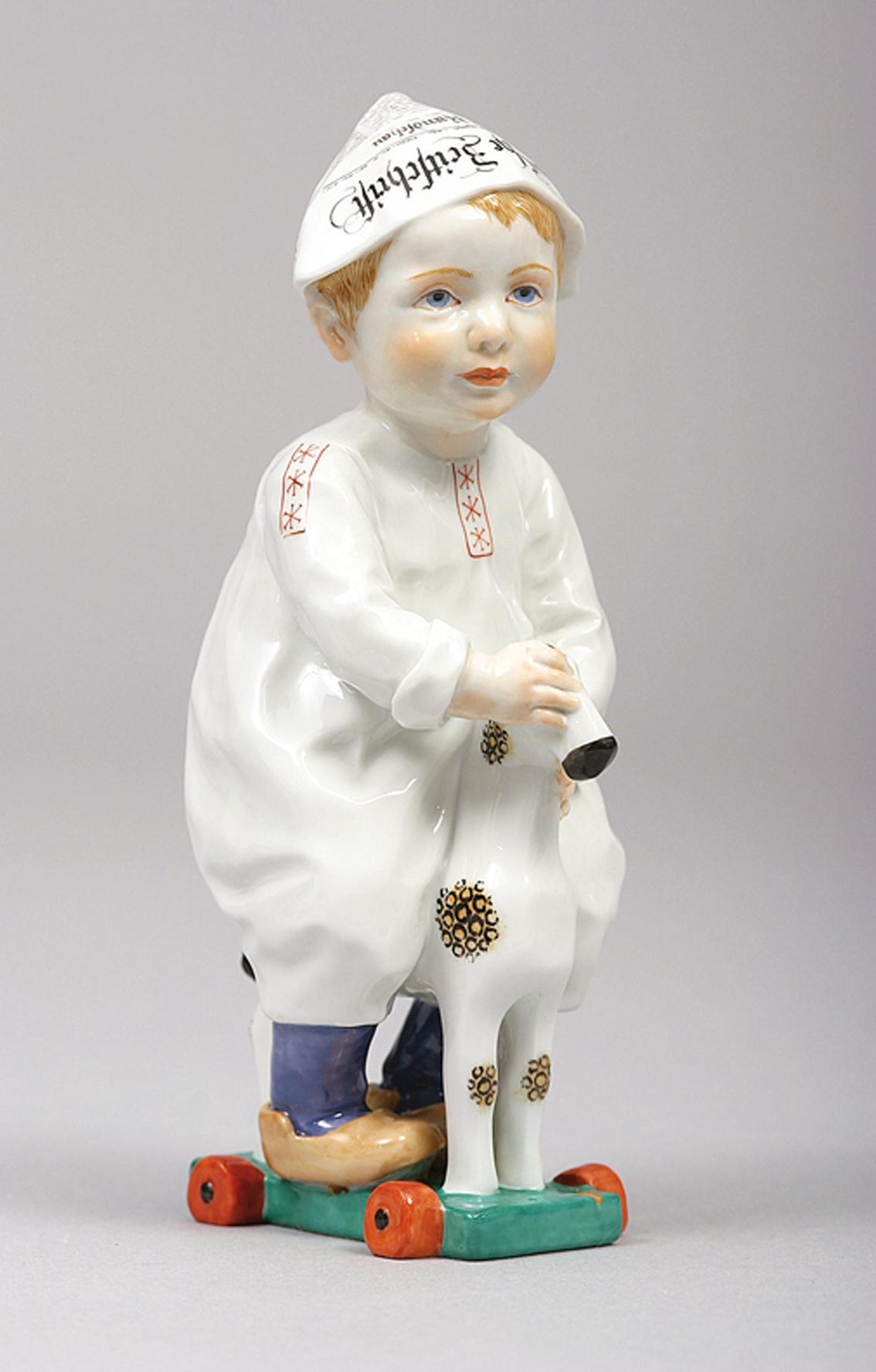 A figure of a Hentschel child 'boy with newsletter cap ridig a wooden horse