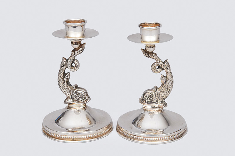 A pair of table candlesticks with dolphin decor
