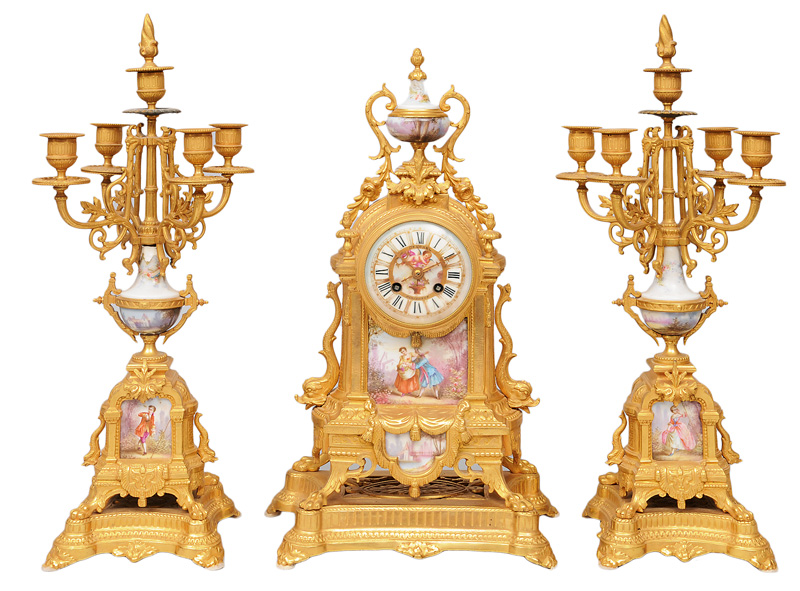 A mantle clock with a pair of candle holders