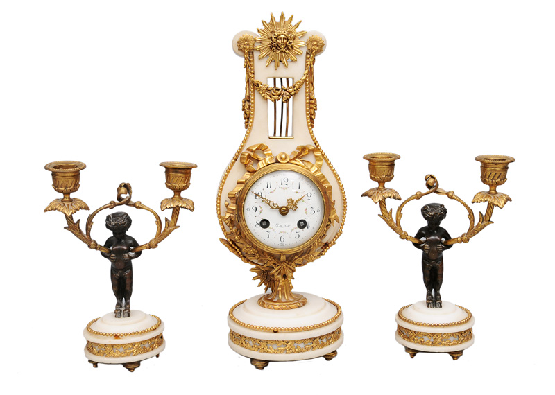 A mantle clock with a pair of candle holders