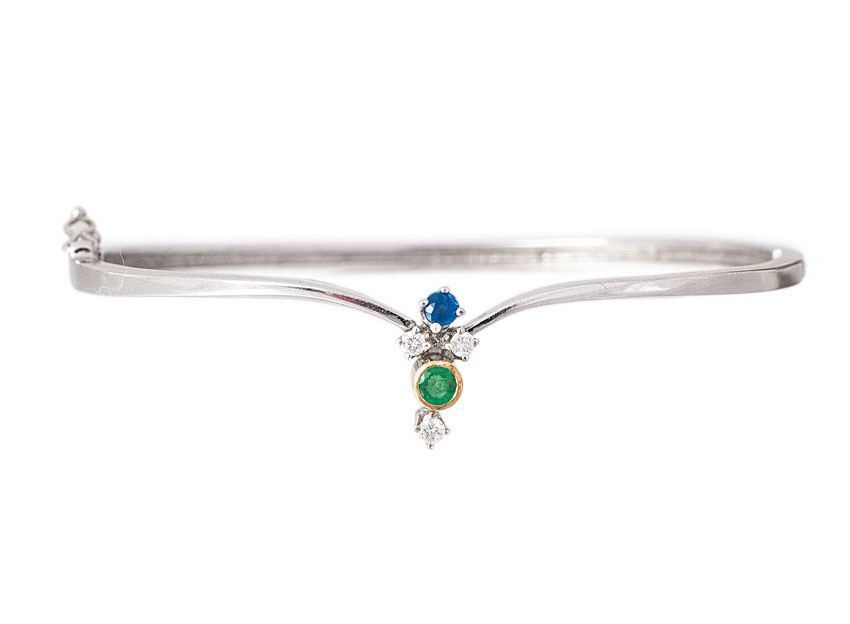 A petite bangle bracelet with sapphire emerald diamond setting