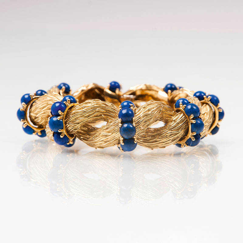 A gold bracelet with woven ornaments and lapis lazuli