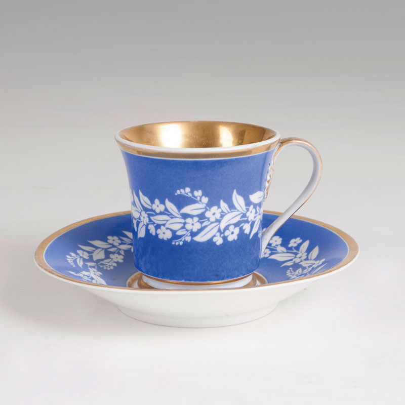 A conical cup with a white floral border on Prussian blue background