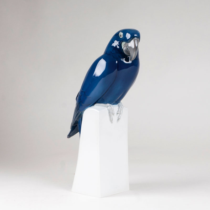 A large porcelain sculpture 'Blue ara on a pedestal'