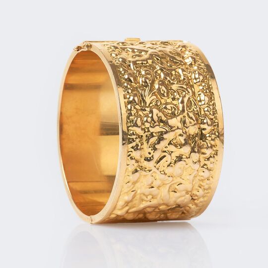 A wide Gold Bangle Bracelet with Relief Frieze